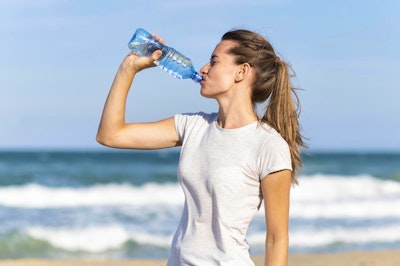 side-view-woman-staying-hydrated-during-beach-workout.jpeg